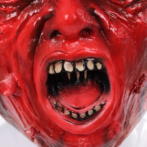 Dettaglio macro della maschera zombie in lattice rosso con trama di muscoli e denti gialli