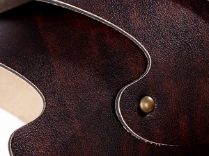 Detailed close-up of dark brown leather texture with vintage brass rivet on spaulder armor