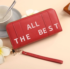 Detail of red litchi texture long wallet with All The Best print and wrist strap