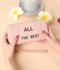 Detailed view of pink long wallet with ALL THE BEST text and wristlet strap detail