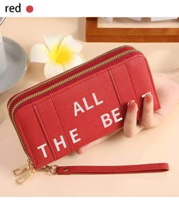 Detail of red long wallet with dual zippers and ALL THE BEST lettering on pebble leather