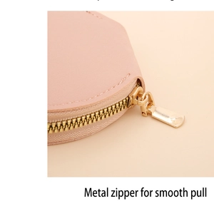 Détail de la fermeture éclair en métal doré sur une pochette en cuir rose souple