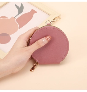 Détail macro du porte-monnaie rond en cuir rose avec fermoir doré et fermeture éclair