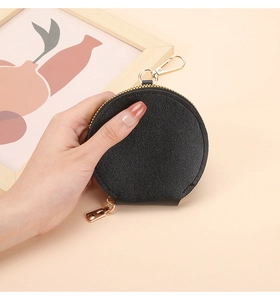 Gros plan d'un porte-monnaie en cuir noir avec texture litchi et crochet doré poli