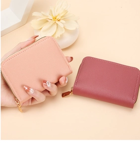 Close-up of compact leather card wallets in pink and orange with gold zippers