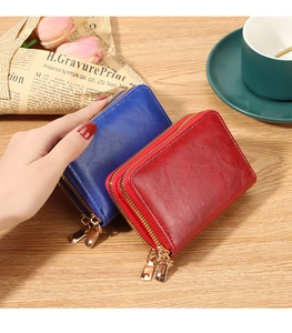 Dual zip leather wallets in navy and burgundy on a desk with elegant lifestyle decor
