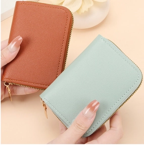 Close-up of caramel and mint green leather card holders with gold zippers on beige background