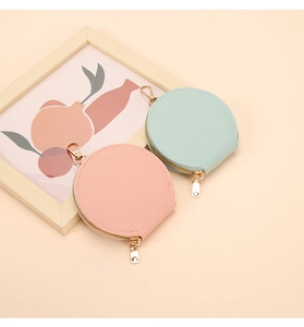 Détail de porte-monnaie ronds en cuir rose et vert menthe avec fermetures éclair dorées