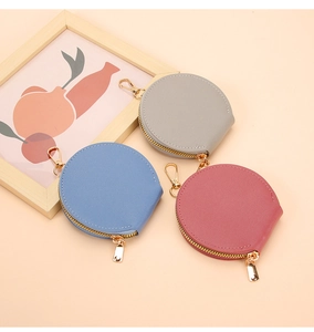 Détail de porte-monnaie ronds en cuir gris, bleu et rose avec crochets métalliques