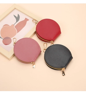 Trois porte-monnaie ronds en cuir coloré avec fermetures éclair dorées et crochets en métal