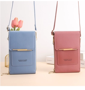 Close-up of blue and pink faux leather crossbody phone bags with gold bar decoration