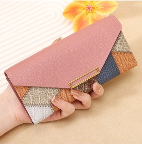 Detail of elegant long wallet with patchwork leather design and gold metal buckle accent