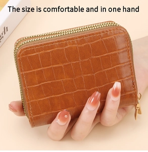 Dettaglio del portafoglio marrone scuro con trama a coccodrillo e doppie zip dorate