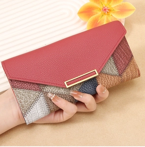 Detail of a women's patchwork long wallet with red pebbled leather and gold metal hardware