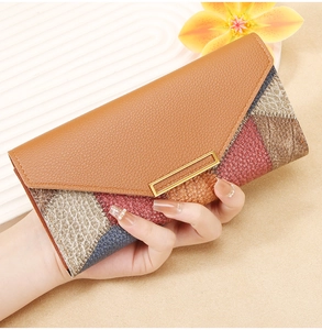 Macro view of long leather wallet featuring colorful patchwork and gold buckle detail