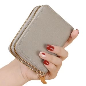 Handheld grey leather accordion card holder with dual zippers and contrast stitching