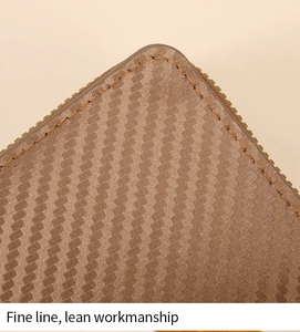 Close-up of brown textured accordion wallet showing fine orange stitching and metal zipper