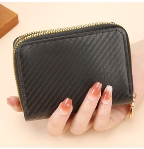 Close-up of double golden zippers and black carbon fiber texture on this compact wallet