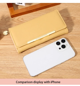 Long yellow leather wallet for women with gold metal bar compared to a smartphone
