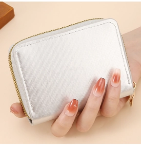 Detail of silver card wallet featuring carbon fiber texture and golden zipper hardware