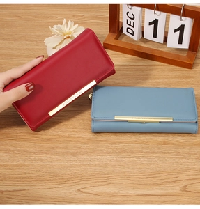 Detail of long leather wallets in red and blue colors with elegant gold metal bar trim