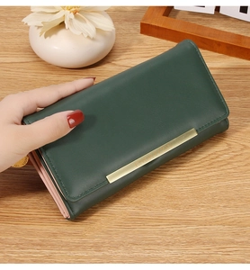 Macro detail of dark green faux leather long wallet with golden decorative hardware bar