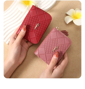 Detail of short wallets in burgundy and pink PU leather with gold logo and tassel zipper