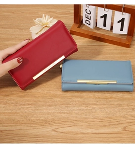 Detail view of red and blue long leather wallets with elegant gold metal trim on cover
