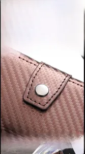 Detail of brown woven leather card holder featuring silver snap and clear ID window