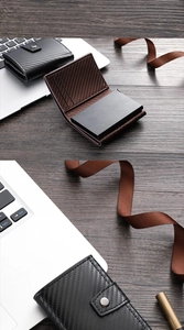 Detail of RFID carbon fiber wallet in black and coffee brown on a wooden desk
