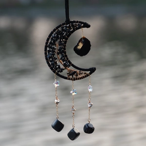 Moon-shaped suncatcher with black natural stones and moonstones hanging by the water