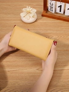 Minimalist long yellow leather wallet for women with fine stitching and zipper closure