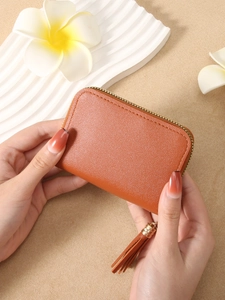 Brown faux leather quilted wallet with gold zipper and tassel held in hands