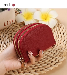 Detail showing red pebble leather texture and dual gold metal zippers on the card holder