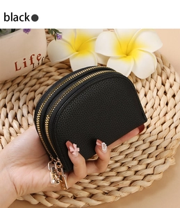 Close-up of black lychee grain leather card holder with dual golden zippers being held