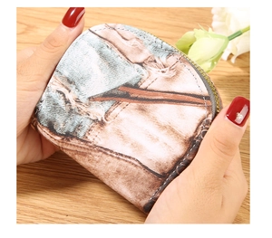 Close-up of a vintage floral pattern coin purse held in hands over a wooden table