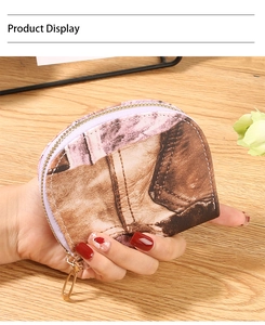 Detail of a semi-circle denim print coin purse with a gold zipper held in hand