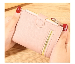 Detail of light pink lychee texture leather wallet with gold zipper being held by hand