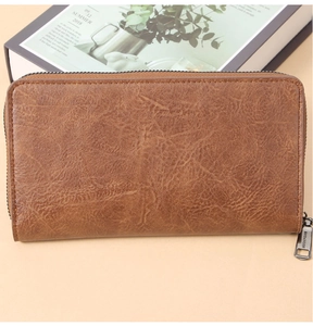 Macro view of vintage brown leather long wallet featuring smooth texture and metal zipper