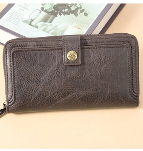Detail of vintage brown leather long wallet with star-shaped bronze snap and stitched texture