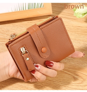 Detailed close-up of small brown litchi pattern wallet with gold zipper held in hand