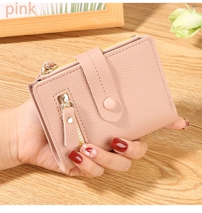 Detailed view of a pink compact leather wallet with pebble texture and gold zipper