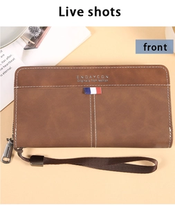 Detail einer braunen langen Brieftasche mit matter Oberfläche und Handschlaufe auf Tisch