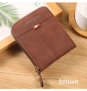 Close-up of brown vintage wallet with decorative ribbon and zipper on a wooden desk