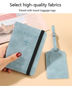Close-up of light blue suede passport holder with elastic strap and matching luggage tag