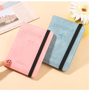 Detail of pink and blue PU leather passport covers with embossed lettering and elastic straps