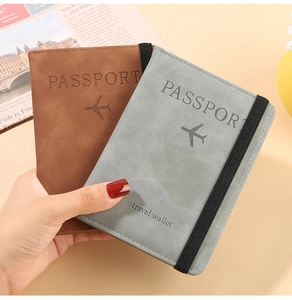 Detail of brown and grey faux suede passport holders with elastic straps and embossed text