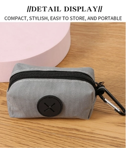 Detail view of a compact gray fabric dog waste bag holder with a black metal carabiner
