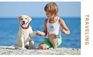 Close-up of boys' white summer vest and green shorts set worn by beach with a puppy