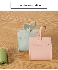 Detail of leather pet waste bag dispensers in mint and pink on wooden surface
